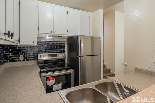 kitchen featuring carpet, appliances with stainless steel finishes, tasteful backsplash, sink, and white cabinets