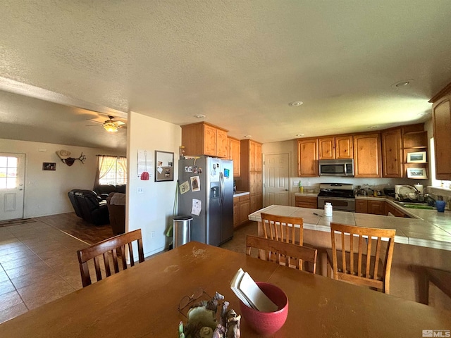 tiled dining room featuring a textured ceiling and ceiling fan