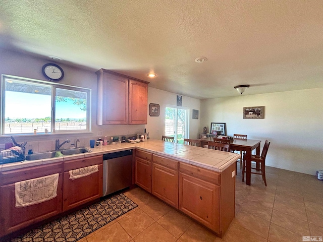 kitchen with stainless steel dishwasher, kitchen peninsula, tile countertops, sink, and light tile floors