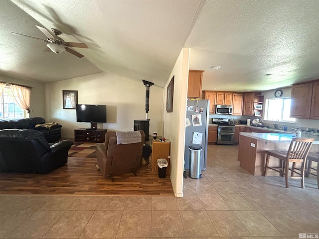 tiled living room with ceiling fan, a healthy amount of sunlight, a textured ceiling, and lofted ceiling