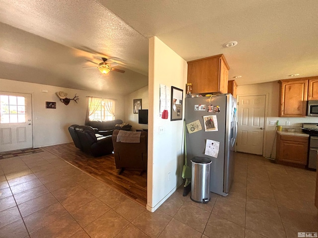 kitchen featuring tile flooring, ceiling fan, lofted ceiling, and appliances with stainless steel finishes