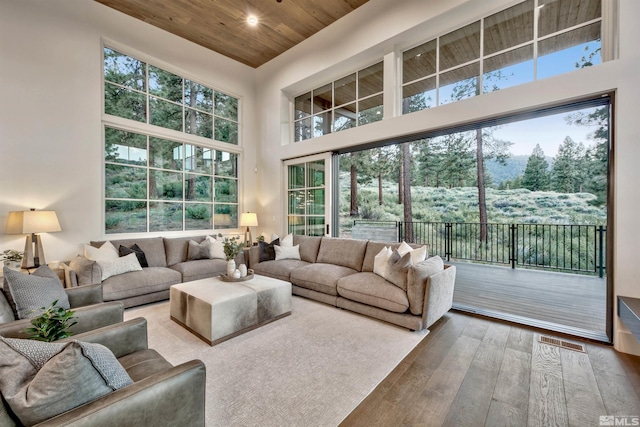 living room with hardwood / wood-style floors, a towering ceiling, and wooden ceiling