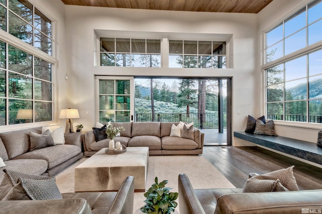 living room with hardwood / wood-style floors, wood ceiling, and a towering ceiling