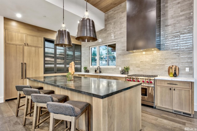 kitchen with light hardwood / wood-style floors, range with two ovens, wall chimney exhaust hood, and sink