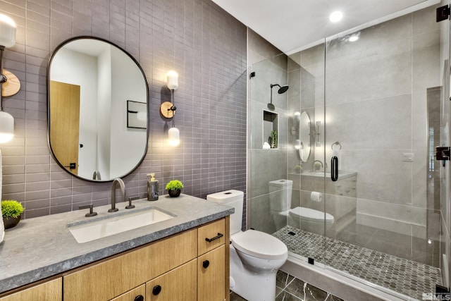 bathroom with vanity, a shower with door, decorative backsplash, toilet, and tile walls