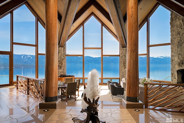 interior space featuring a wall of windows, high vaulted ceiling, and a water and mountain view