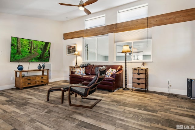 living room featuring ceiling fan, wood-type flooring, and a high ceiling