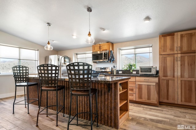 kitchen with a wealth of natural light, stainless steel appliances, pendant lighting, a center island, and a breakfast bar area