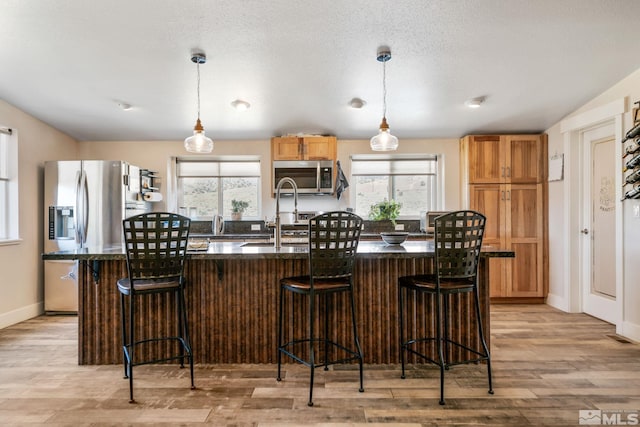 kitchen with a breakfast bar, stainless steel appliances, light hardwood / wood-style flooring, and plenty of natural light