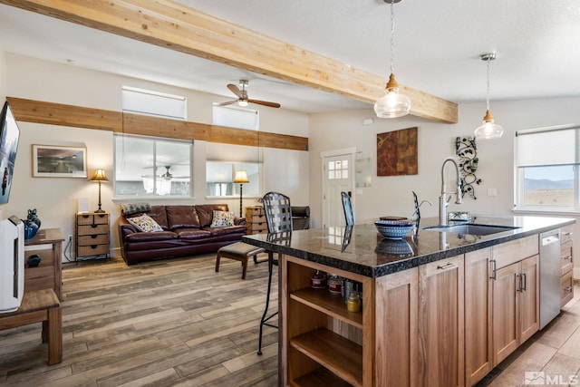 kitchen featuring dishwasher, a center island with sink, sink, decorative light fixtures, and beam ceiling