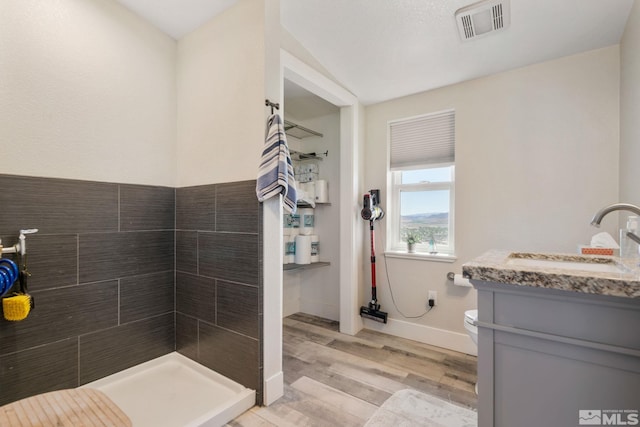 bathroom with a shower, hardwood / wood-style floors, vanity, and toilet