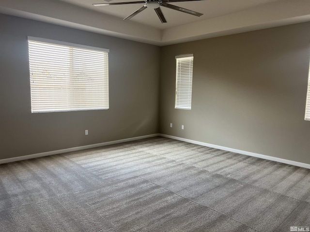 empty room with carpet flooring, ceiling fan, and a tray ceiling