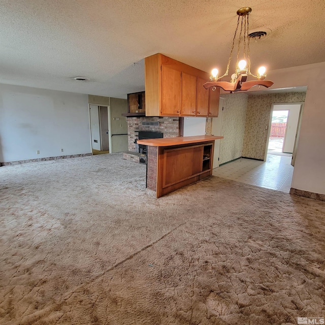 kitchen with hanging light fixtures, a textured ceiling, light colored carpet, kitchen peninsula, and a chandelier