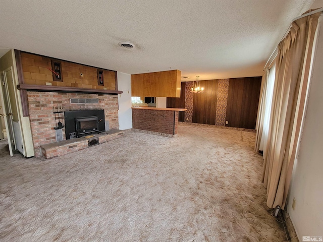 unfurnished living room featuring carpet flooring, a fireplace, a chandelier, and wood walls