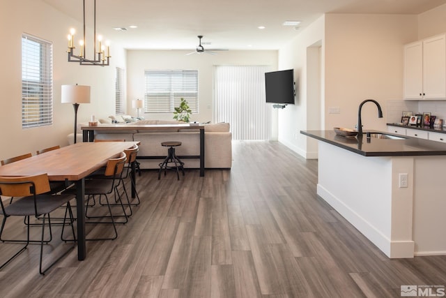 dining room featuring ceiling fan with notable chandelier, dark hardwood / wood-style flooring, and sink