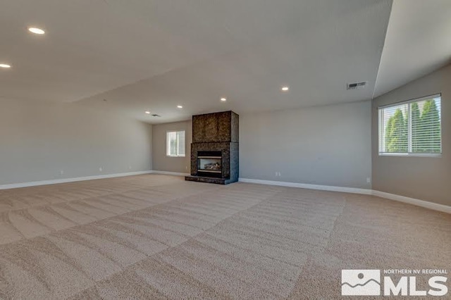 unfurnished living room featuring light colored carpet, a tile fireplace, and baseboards