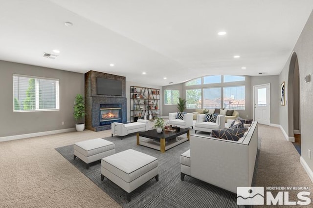 living room with vaulted ceiling, a fireplace, visible vents, and baseboards