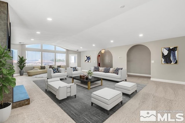 carpeted living area with arched walkways, recessed lighting, baseboards, and vaulted ceiling