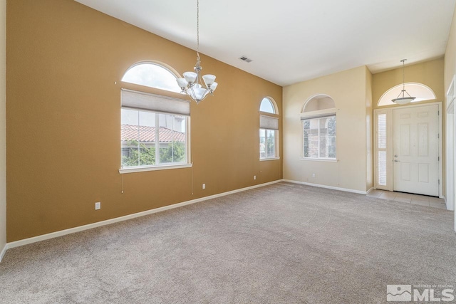 carpeted empty room featuring a chandelier