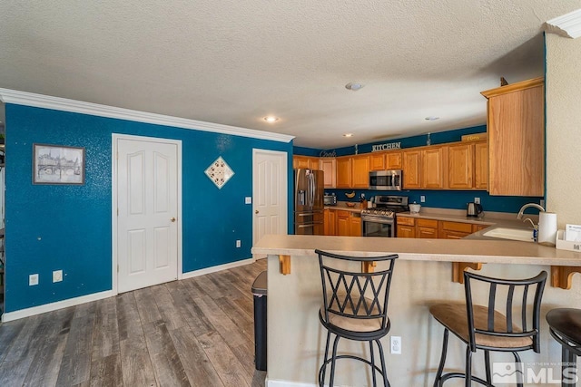 kitchen with a kitchen breakfast bar, sink, ornamental molding, and appliances with stainless steel finishes