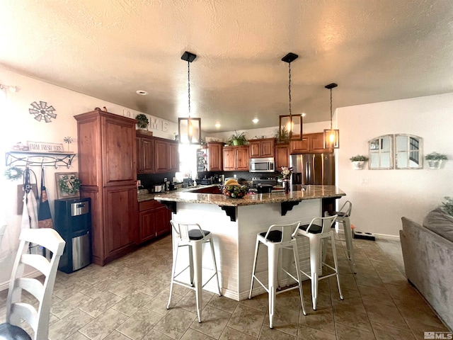 kitchen featuring a center island, stainless steel appliances, a breakfast bar area, decorative light fixtures, and light tile floors