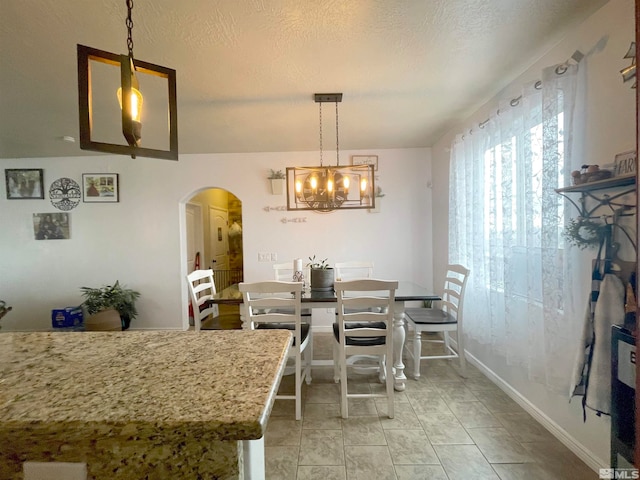 tiled dining room with a textured ceiling and an inviting chandelier