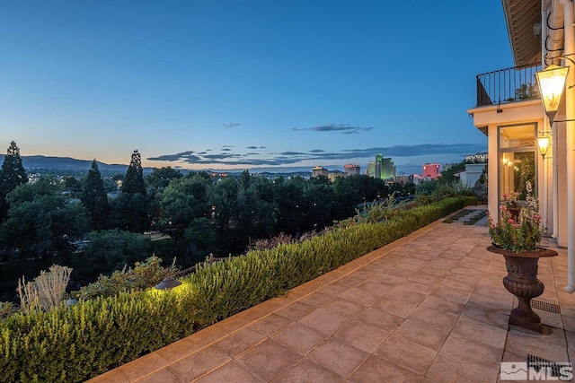 patio terrace at dusk featuring a balcony