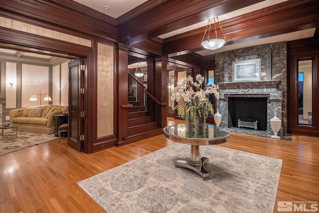 interior space with a high end fireplace, ornamental molding, stairway, and wood finished floors