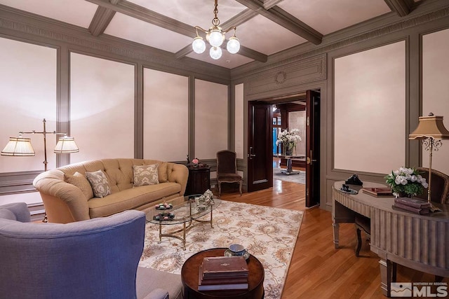 living area with a decorative wall, coffered ceiling, light wood-type flooring, and beam ceiling