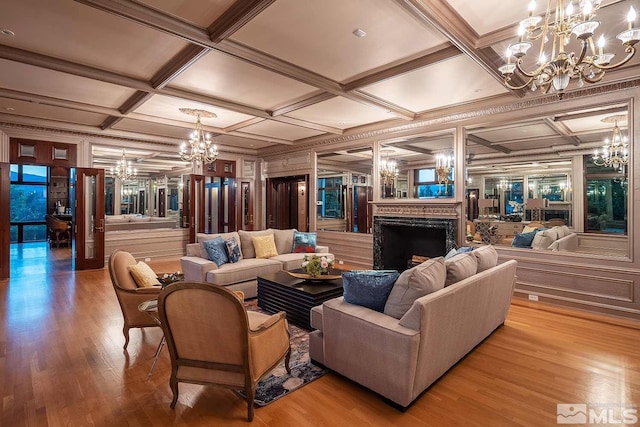 living area with a fireplace, coffered ceiling, a chandelier, and wood finished floors