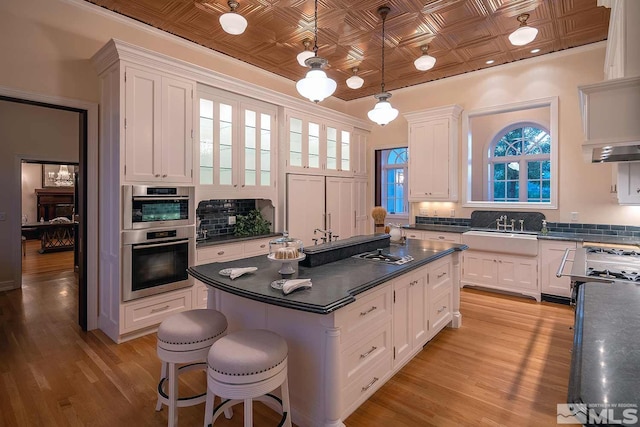 kitchen featuring an ornate ceiling, dark countertops, white cabinets, and a sink