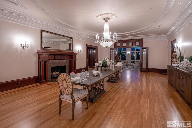 dining space with ornamental molding, a notable chandelier, a fireplace, and wood finished floors