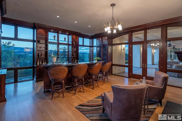 bar with french doors, an inviting chandelier, and light wood-style floors