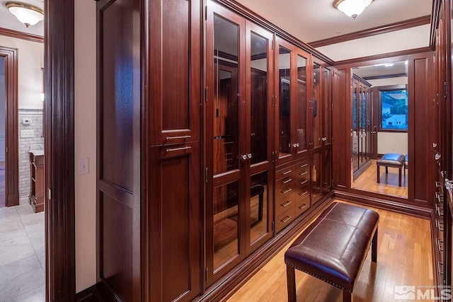 hallway with light wood finished floors and crown molding