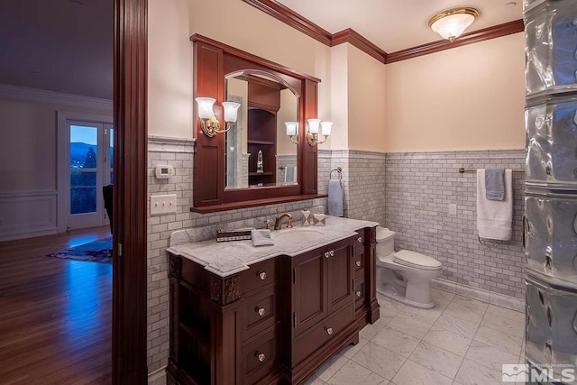 bathroom with a wainscoted wall, ornamental molding, toilet, and vanity