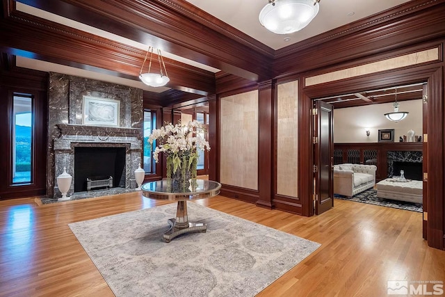 living room with beamed ceiling, crown molding, light hardwood / wood-style flooring, and a fireplace