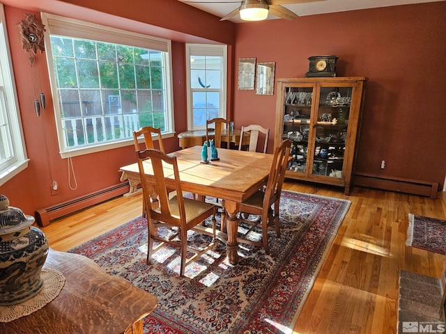 dining room with ceiling fan, light wood-type flooring, and a baseboard heating unit