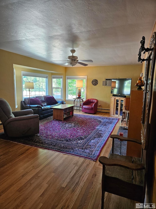 living room featuring ceiling fan, wood-type flooring, a textured ceiling, and baseboard heating