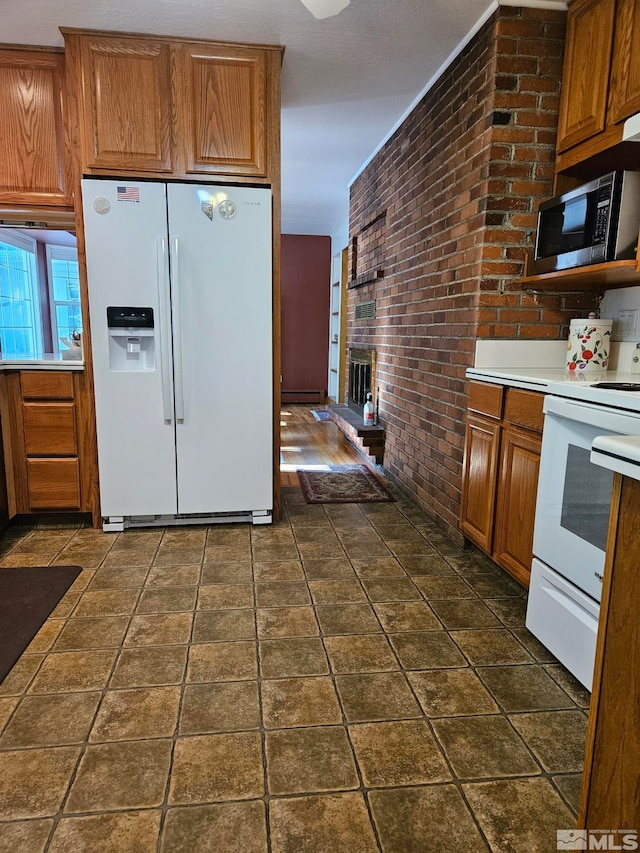 kitchen featuring a fireplace, white appliances, and brick wall