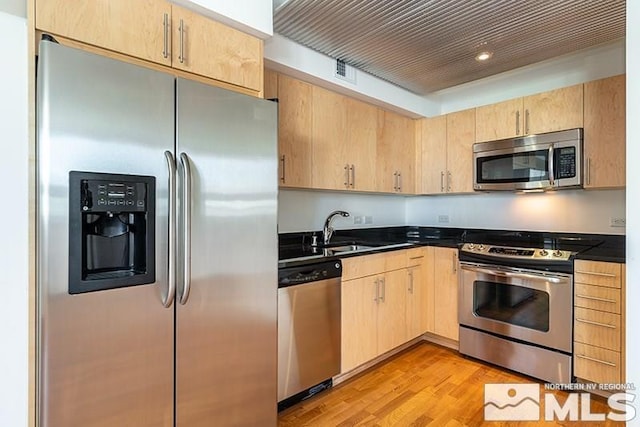 kitchen featuring light brown cabinets, sink, light wood-type flooring, and stainless steel appliances