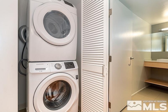 laundry room featuring tile patterned floors and stacked washer / drying machine