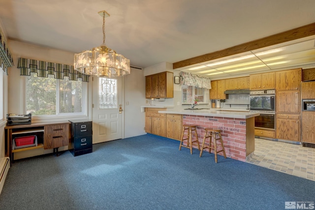 kitchen featuring carpet, a kitchen breakfast bar, kitchen peninsula, hanging light fixtures, and double oven