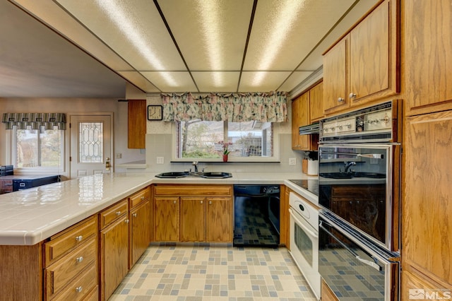 kitchen featuring sink, black dishwasher, decorative backsplash, and kitchen peninsula