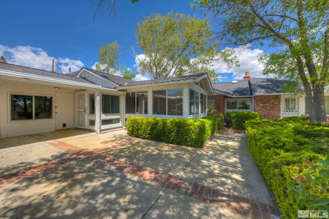 rear view of property with a sunroom and a patio