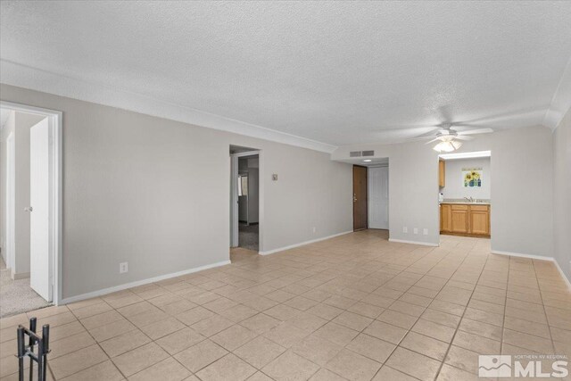 tiled spare room with ceiling fan, sink, and a textured ceiling