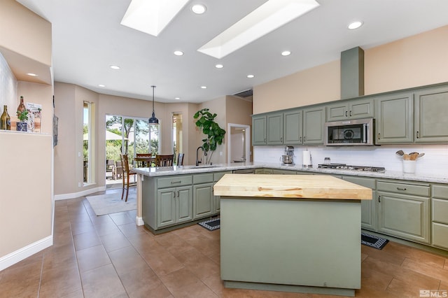 kitchen with a center island, green cabinets, hanging light fixtures, a skylight, and stainless steel appliances