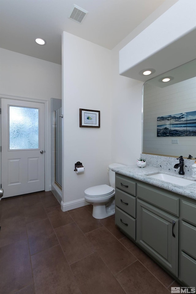 bathroom with tile patterned floors, vanity, toilet, and a shower with door