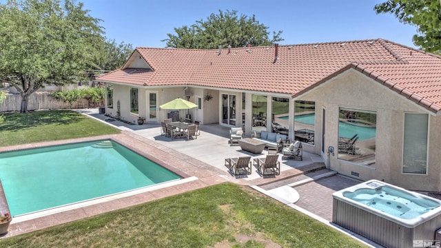 back of house with outdoor lounge area, a swimming pool with hot tub, a patio, and a lawn