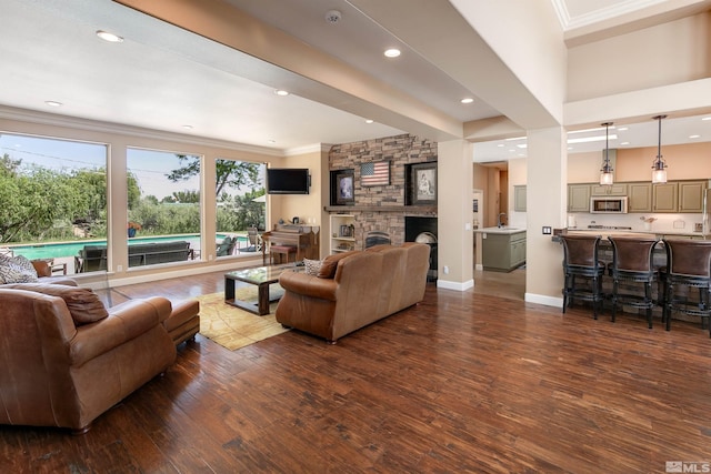 living room with dark hardwood / wood-style flooring, crown molding, and a fireplace