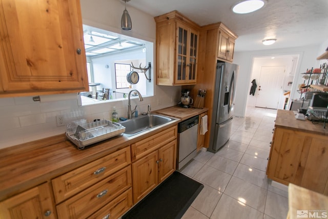 kitchen featuring decorative light fixtures, light tile patterned floors, tasteful backsplash, appliances with stainless steel finishes, and sink